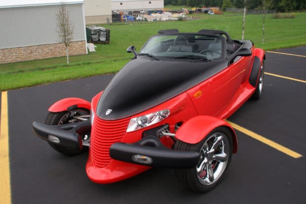 A red and black Plymouth Prowler with chrome wheels parked on asphalt near greenery, 2K Desktop Wallpaper
