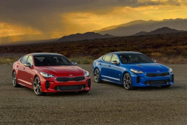 Two Kia Stinger vehicles parked on a gravel surface with mountains in the background, HD Desktop Wallpaper