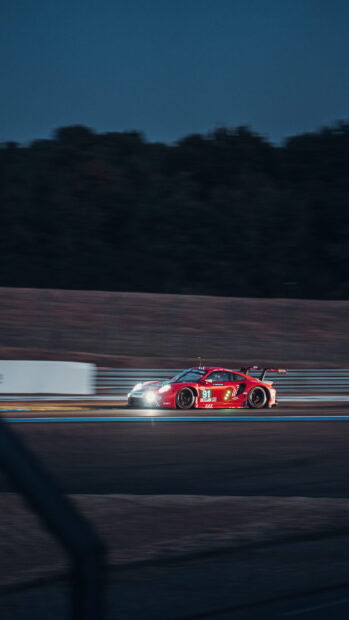 A red race car is driving fast on the race track at dusk, HD Phone Wallpaper