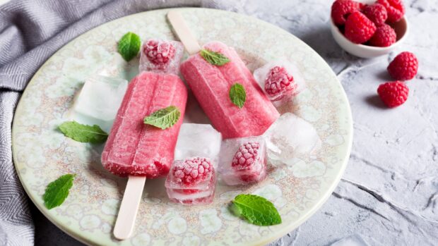Two red raspberry popsicles laid on a detailed plate surrounded by ice cubes and fresh mint leaves, 4K Desktop Wallpaper