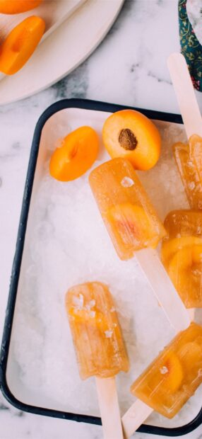 A close up of apricot popsicles with fresh apricot halves on ice, 2K Mobile Wallpaper
