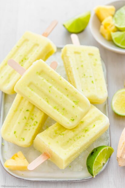 A close up of lime and pineapple popsicles on ice with fresh fruit slices, 2K Mobile Wallpaper