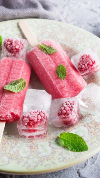 Pink popsicles with mint and raspberry ice cubes on a decorative plate, 2K Phone Wallpaper