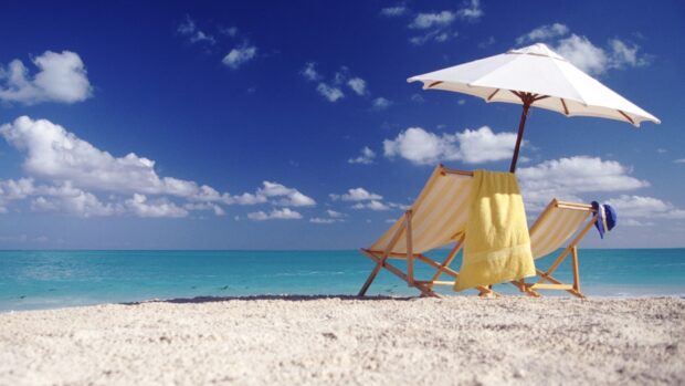 A beach umbrella and two chairs are set up on the sand with a bright blue sea and sky, HD Desktop Wallpaper