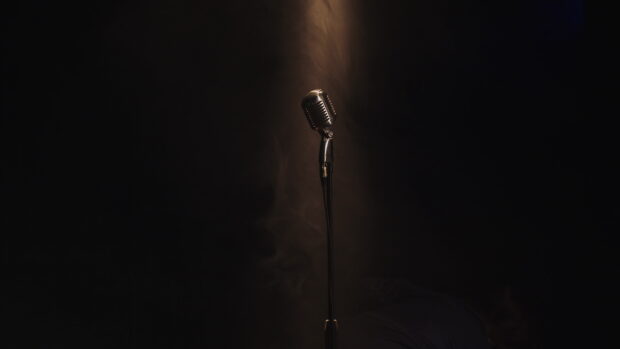 A vintage microphone illuminated by a single spotlight in a dark room, 4K Desktop Wallpaper