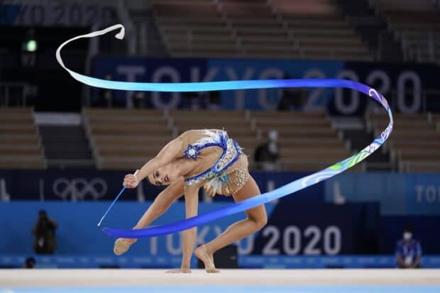 A rhythmic gymnastics athlete executes a balance move with a flowing ribbon at the Tokyo 2020 Olympics, 2K Desktop Wallpaper