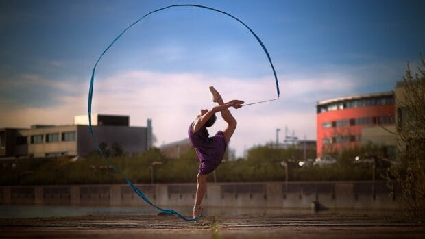 A rhythmic gymnastics athlete performing an elegant pose with a blue ribbon outdoors, HD Desktop Wallpaper