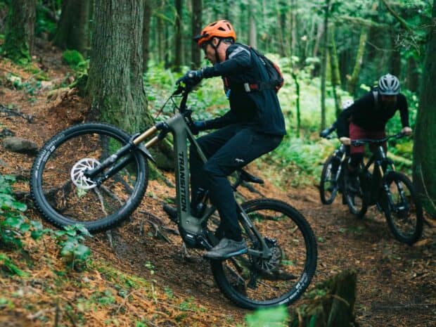 Two riders enjoy off road cycling on Transition bikes in a dense forest, HD Desktop Wallpaper