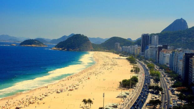 A scenic view of Rio De Janeiro with crowded beach and city buildings under a clear sky, HD Desktop Wallpaper