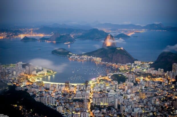The Rio De Janeiro cityscape shows illuminated buildings and mountains, 2K Desktop Wallpaper