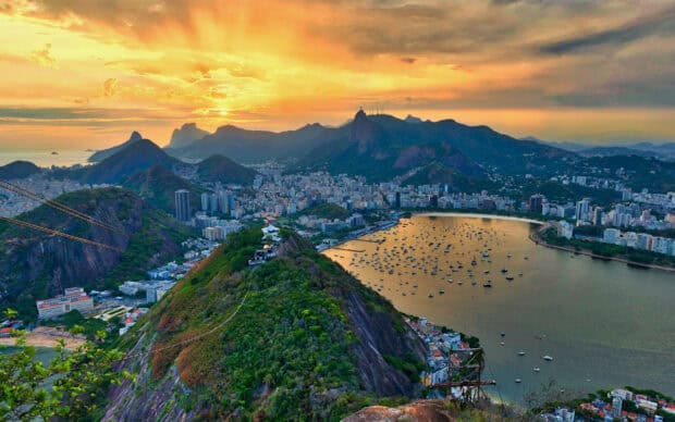 The cityscape of Rio De Janeiro features mountains and boats during sunset, 2K Desktop Wallpaper