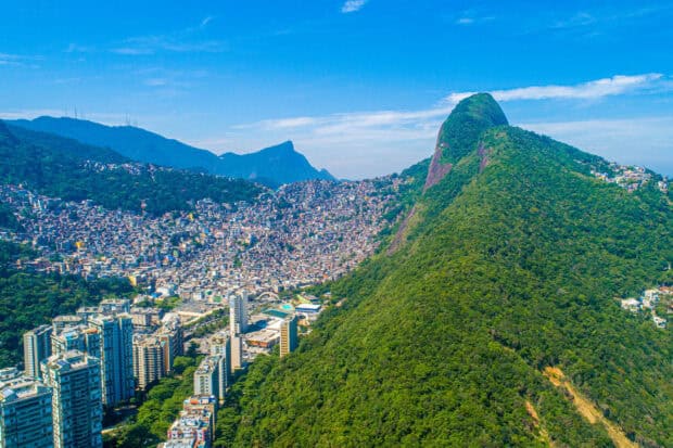 A scenic aerial view of Rio De Janeiro with lush green mountains and urban buildings, 2K Desktop Wallpaper