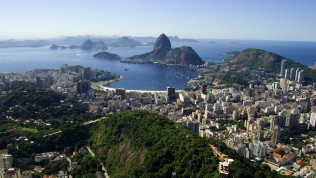 A panoramic view of Rio De Janeiro city features Sugarloaf Mountain and surrounding beaches under clear skies, 4K Desktop Wallpaper