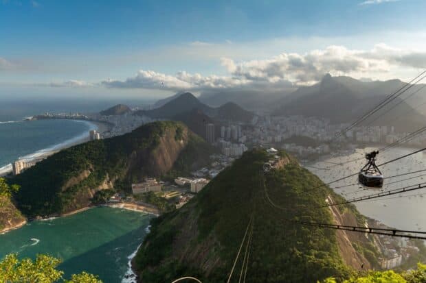 A view of Rio De Janeiro highlighting the mountains and a cable car over the city near the ocean, HD Desktop Wallpaper