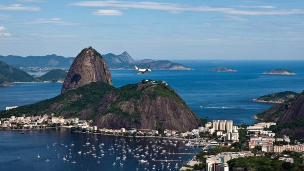 A plane flies over Rio de Janeiro's iconic Sugarloaf Mountain and marina, HD Desktop Wallpaper