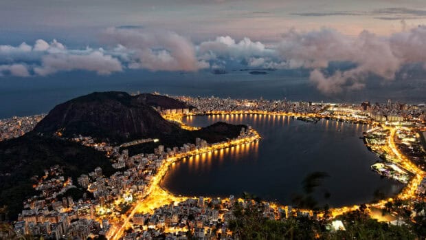 The Rio De Janerio Wallpapers cityscape shows illuminated streets and hills under a cloudy evening sky, 4K Desktop Wallpaper