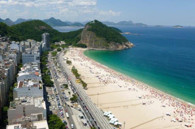 A crowded beach and green mountain can be seen along the coastline of Rio de Janeiro, Brazil, 2K Desktop Wallpaper