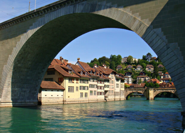 A beautiful scene of River Aare Switzerland under a stone bridge with houses nearby, HD Desktop Wallpaper