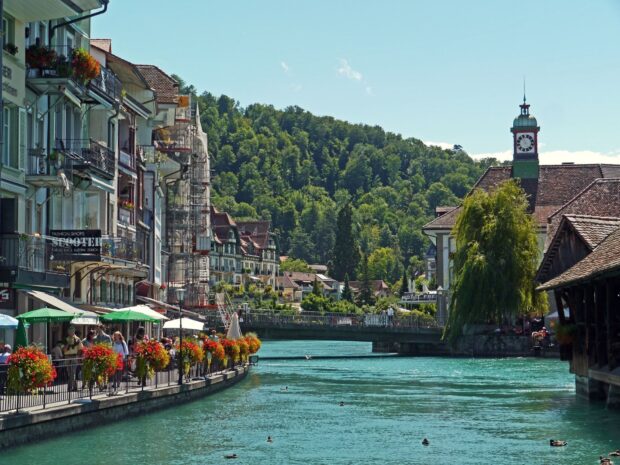 The River Aare in Switzerland flows past colorful buildings and a bridge under a clear sky, HD Desktop Wallpaper