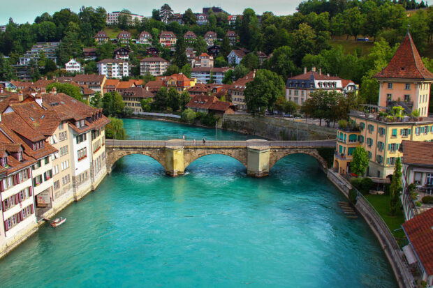 The River Aare flows peacefully under the old stone bridge surrounded by Swiss townhouses and greenery, HD Desktop Wallpaper