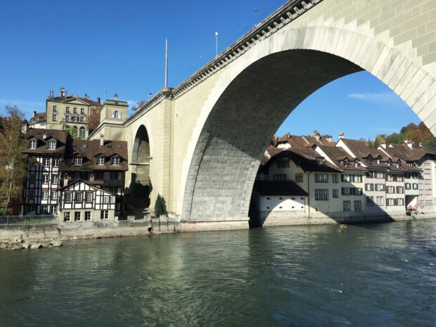 The river Aare flows calmly beneath the old stone bridge in Switzerland with houses along the shore, HD Desktop Wallpaper