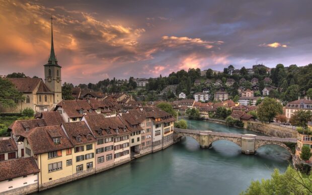 The River Aare flows through historic Swiss town under a dramatic sunset sky, HD Desktop Wallpaper