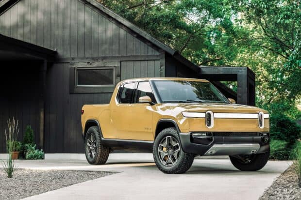 A Rivian Automotive truck is parked near a modern house surrounded by trees, HD Desktop Wallpaper