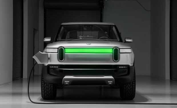 A white Rivian electric vehicle is shown charging in a modern garage, HD Desktop Wallpaper