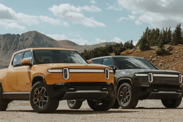 Two Rivian automotive trucks are parked on a mountain road under a cloudy sky, 2K Desktop Wallpaper