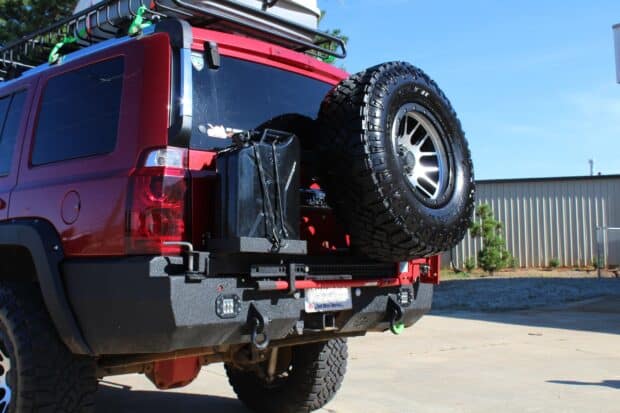 A red Jeep Commander is parked outdoors with a mounted spare tire and fuel container on the back, 2K Desktop Wallpaper