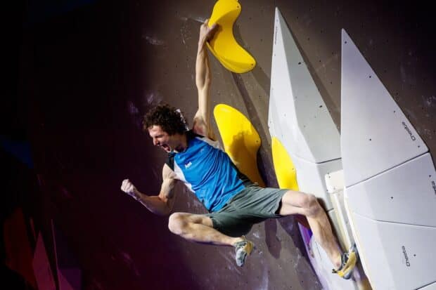A climber celebrating with a fist pump on a challenging climbing wall, 2K Mobile Wallpaper