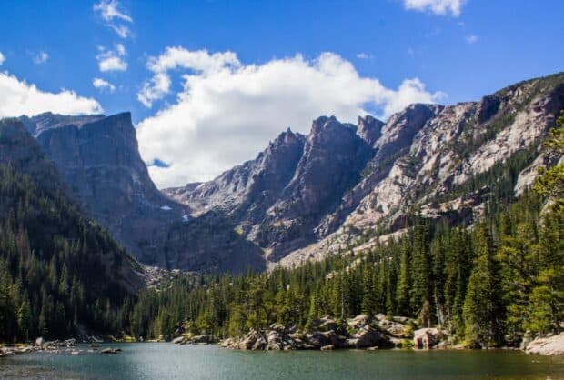 A lake with tall pine trees and rugged mountains under a blue sky in Rocky Mountain National Park, HD Desktop Wallpaper