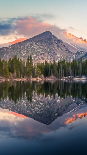 A mountain peak reflects in a calm lake surrounded by pine trees during sunset in Rocky Mountain National Park, 4K Phone Wallpaper