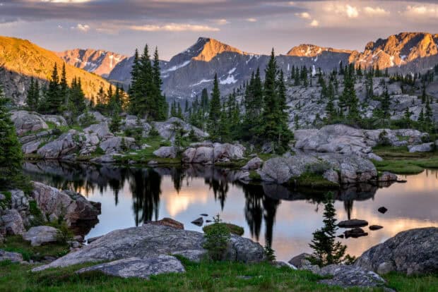 A peaceful lake surrounded by rocky terrain and pine trees in Rocky Mountain National Park, HD Desktop Wallpaper