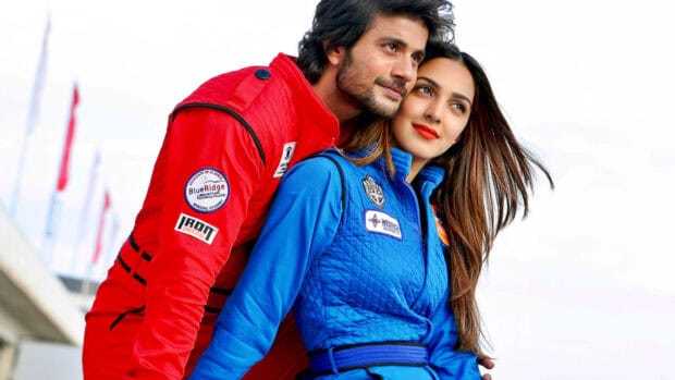 A Bollywood couple in brightly colored jackets sharing a tender moment outdoors, HD Desktop Wallpaper
