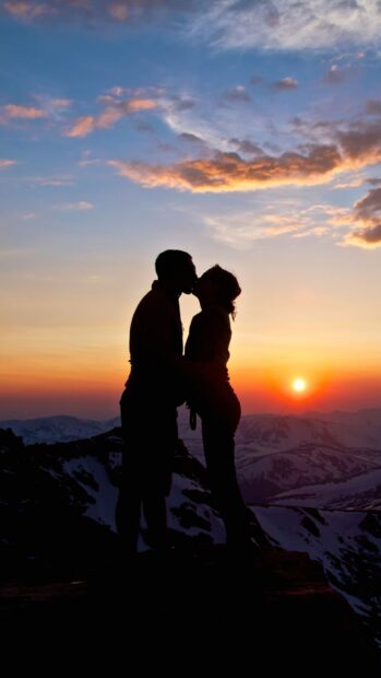 A couple is kissing on a mountain during sunset with colorful sky and snow in the background, HD Mobile Wallpaper