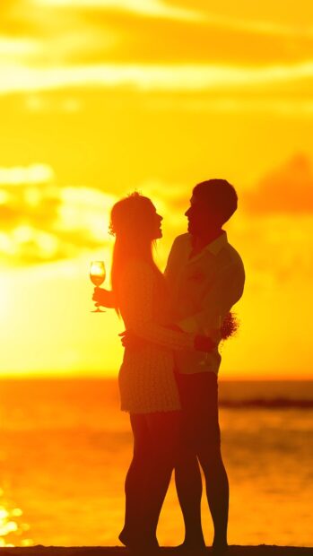 A loving couple embraces by the ocean during a golden sunset, HD Mobile Wallpaper