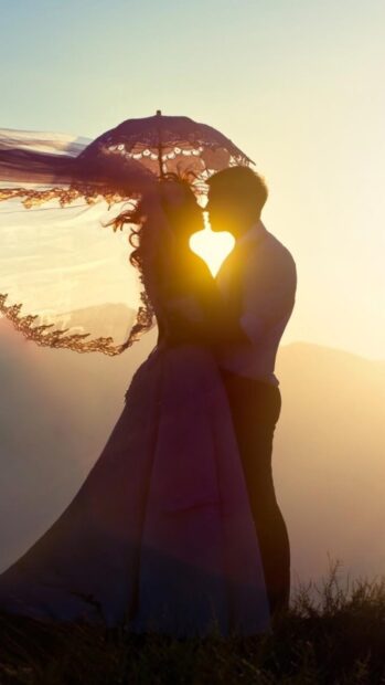 A love couple wallpapers showing a romantic couple kissing with the sun shining behind them, 4K Phone Wallpaper