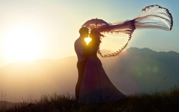 A couple shares a romantic kiss under the glowing sunset with a flowing veil, 2K Desktop Wallpaper