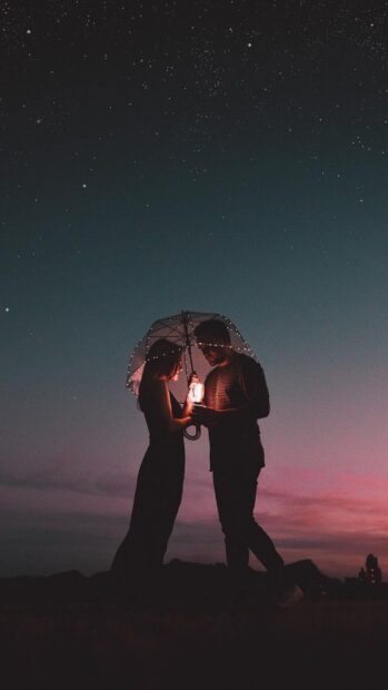 A couple sharing a quiet moment under a lit umbrella at night, HD Phone Wallpaper