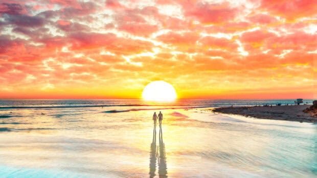 A love couple walking hand in hand on the beach during a colorful sunset, 4K Desktop Wallpaper