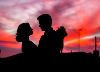 A love couple is shown in silhouette against a colorful sunset sky, 4K Desktop Wallpaper