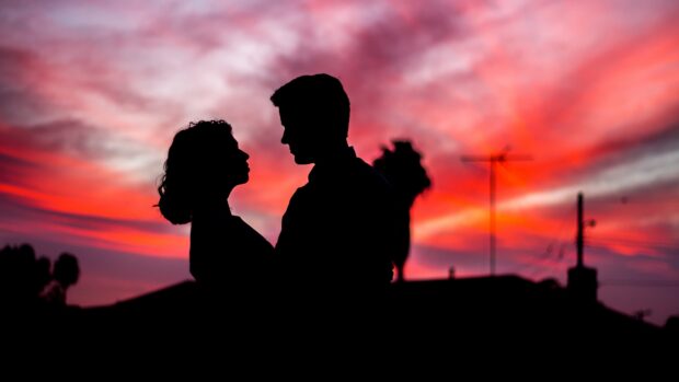 A love couple is shown in silhouette against a colorful sunset sky, 4K Desktop Wallpaper
