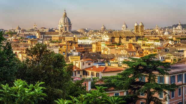 A panoramic view of Rome skyline with historic domes and rooftops under clear sky, 2K Desktop Wallpaper