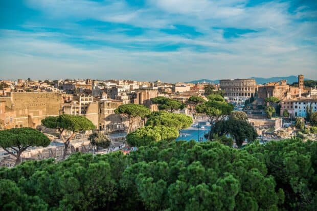The Rome skyline displays ancient structures and lush trees under a blue sky, HD Desktop Wallpaper