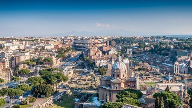 The Rome skyline features ancient architecture and lush greenery under a clear blue sky, HD Desktop Wallpaper