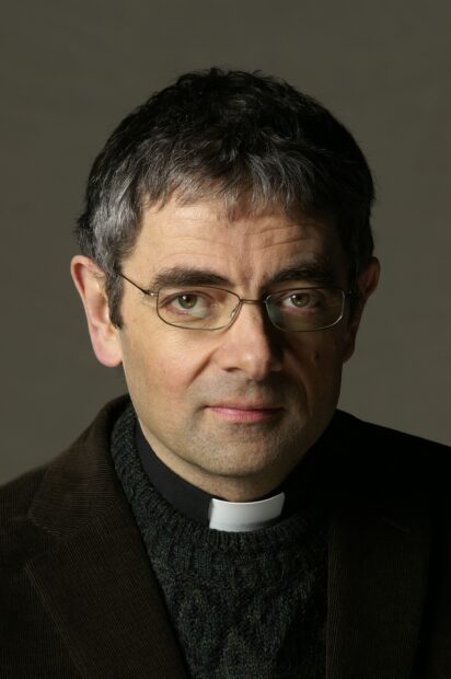 Rowan Atkinson with glasses wearing a clerical collar in a close up portrait, 2K Mobile Wallpaper