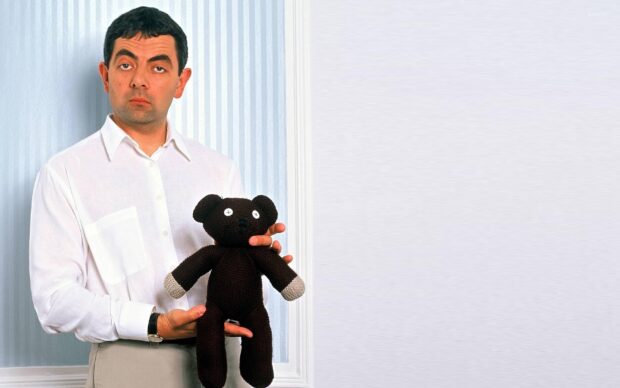 Rowan Atkinson wallpapers shows a man in a white shirt holding a knitted black teddy bear with button eyes, HD Desktop Wallpaper