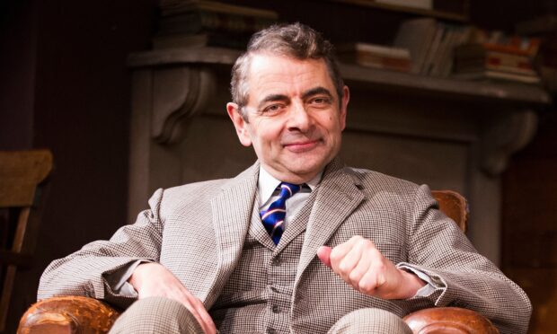 Rowan Atkinson in a classic suit sitting comfortably with a slight smile, HD Desktop Wallpaper