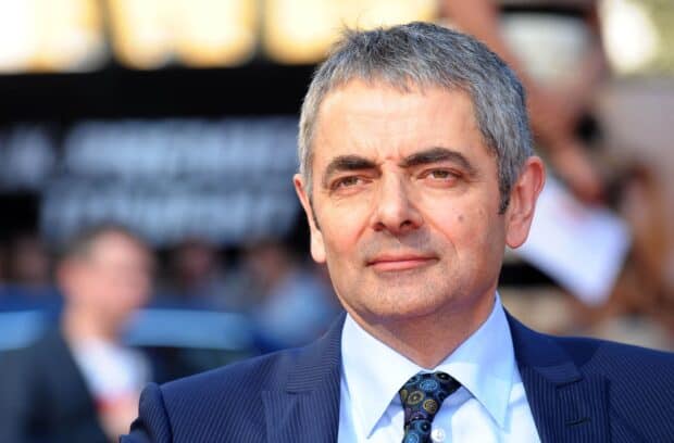 Rowan Atkinson wallpapers showing a man in a blue suit with a patterned tie outdoors, 2K Desktop Wallpaper